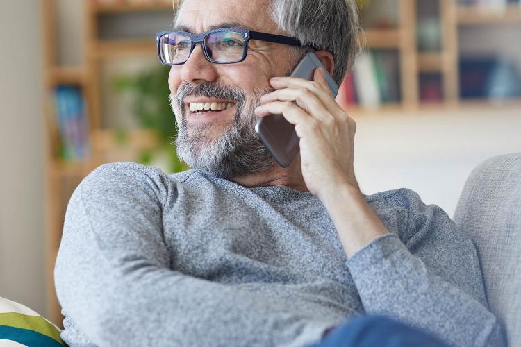Mann auf dem Sofa telefoniert mit dem Smartphone.