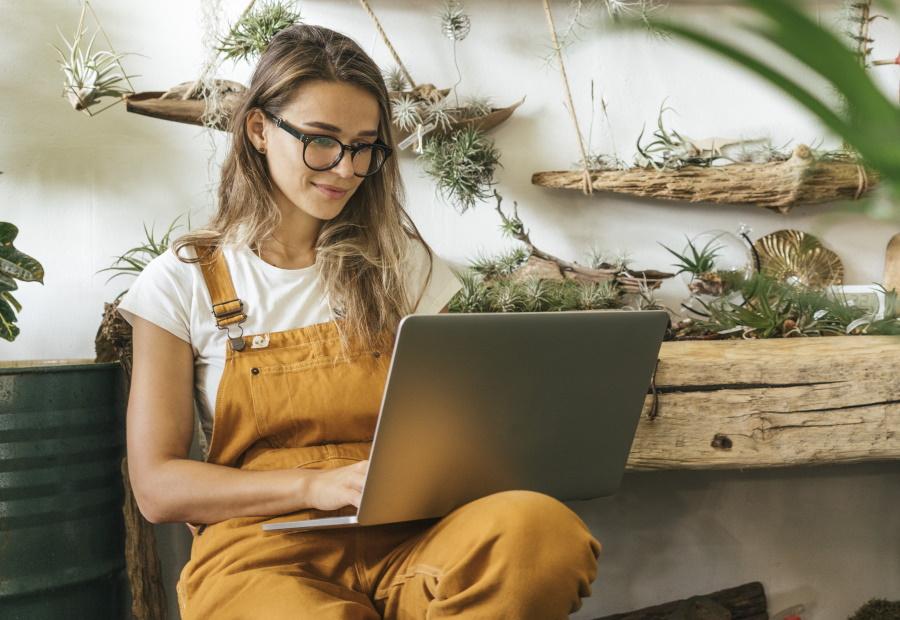 Ein junges Paar sitzt mit seinem Hund auf der Couch und schaut etwas im Laptop nach