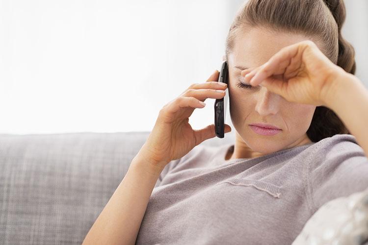 Frau telefoniert am Handy und fasst sich verzweifelt an den Kopf
