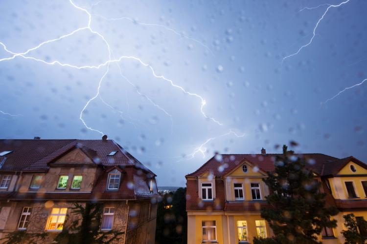 Blitze am verregneten Himmel über Häuserreihe