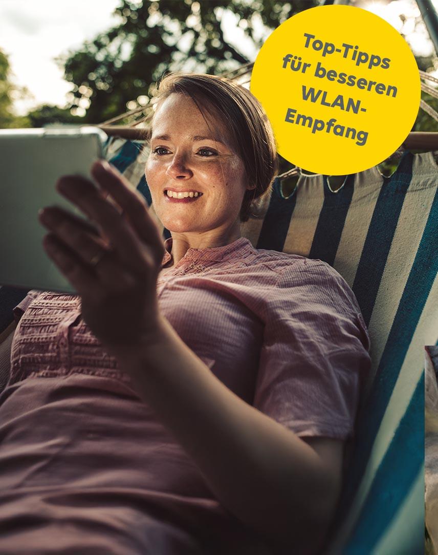 Frau in Hängematte liegend schaut aufs Tablet.