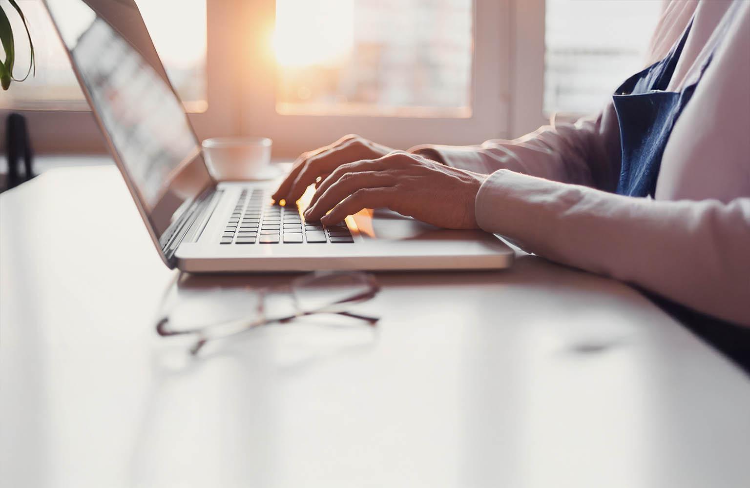 Hände tippen auf einer Laptop-Tastatur