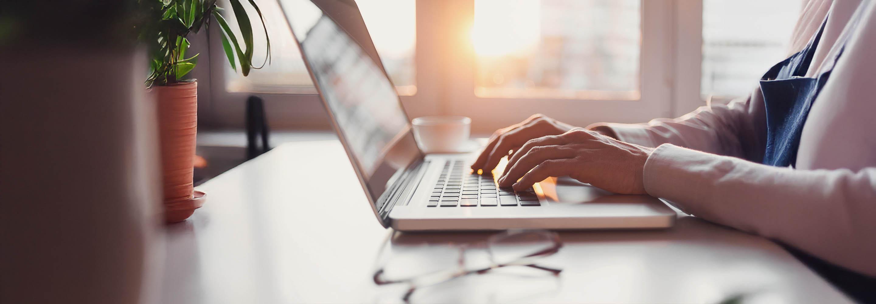 Hände tippen auf einer Laptop-Tastatur