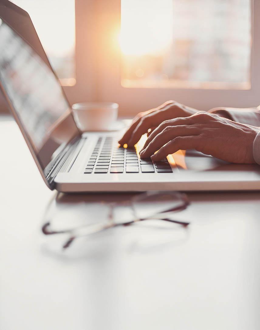 Hände tippen auf einer Laptop-Tastatur