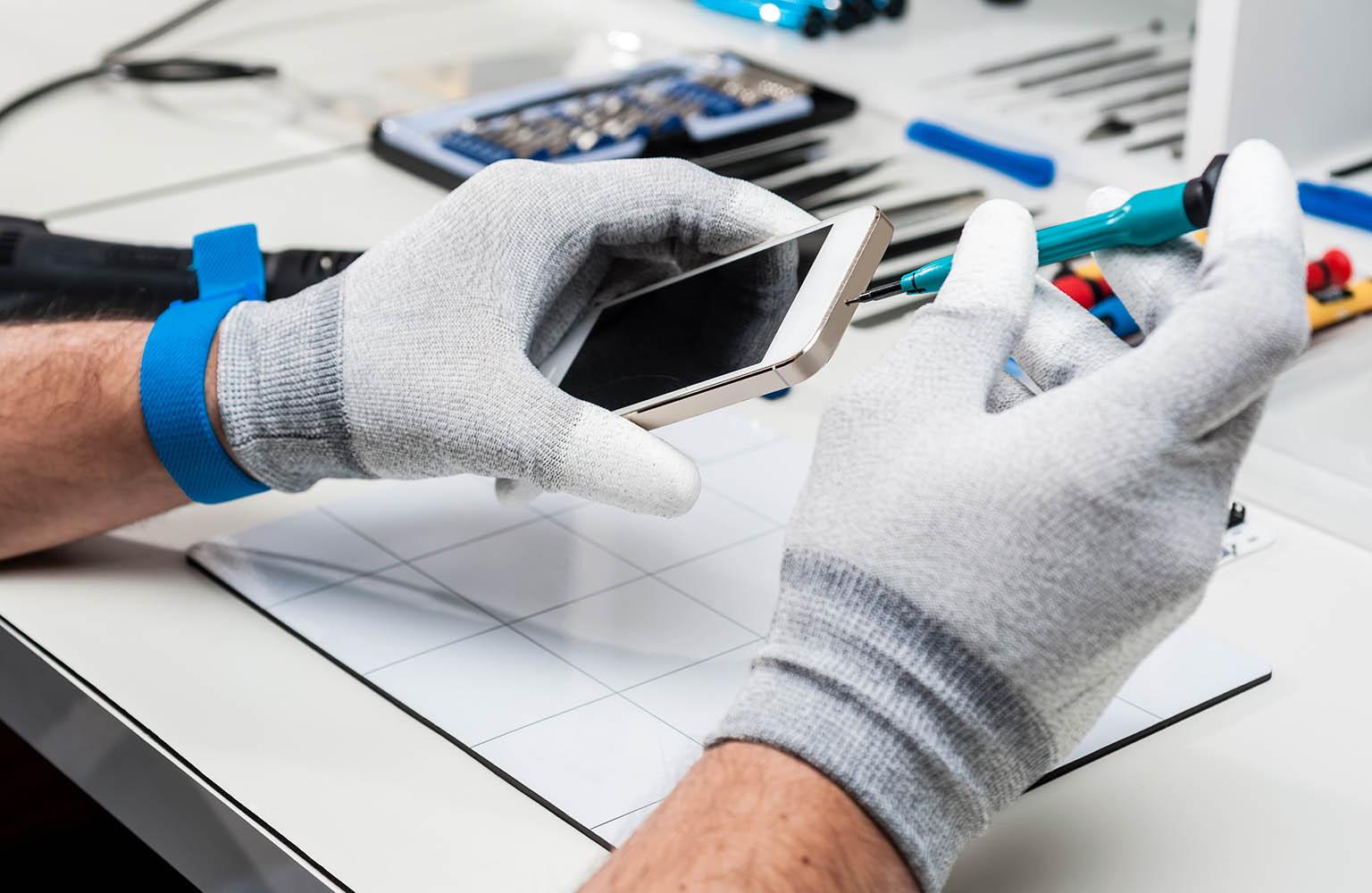Hände mit Handschuhen öffnen Smartphone-Gehäuse.