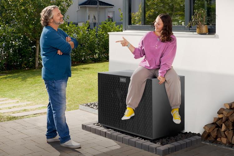 Vater und Tochter, die auf einer Wärmepumpe sitzt, unterhalten sich in ihrem Garten