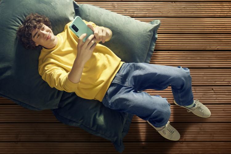 Jugendlicher Junge in gelbem Pulli macht liegend ein Selfie von sich