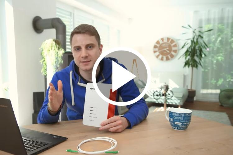 EWE-Smartgeber Jan sitzt im Wohnzimmer und hält einen Router in der Hand