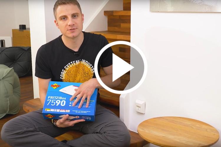 EWE-Smartgeber Jan sitzt im Wohnzimmer und hält einen Router-Karton in der Hand